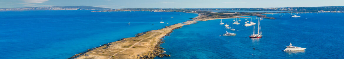 view over the turquoise water of the beach of formentera with some charter yachts