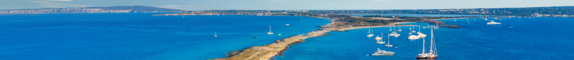 view over the turquoise water of the beach of formentera with some charter yachts