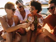 multiracial group of people toasting drinks on the yacht deck